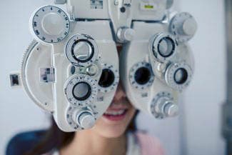Patient looking through a phoropter during an eye exam at Mill Creek Family Eye Center